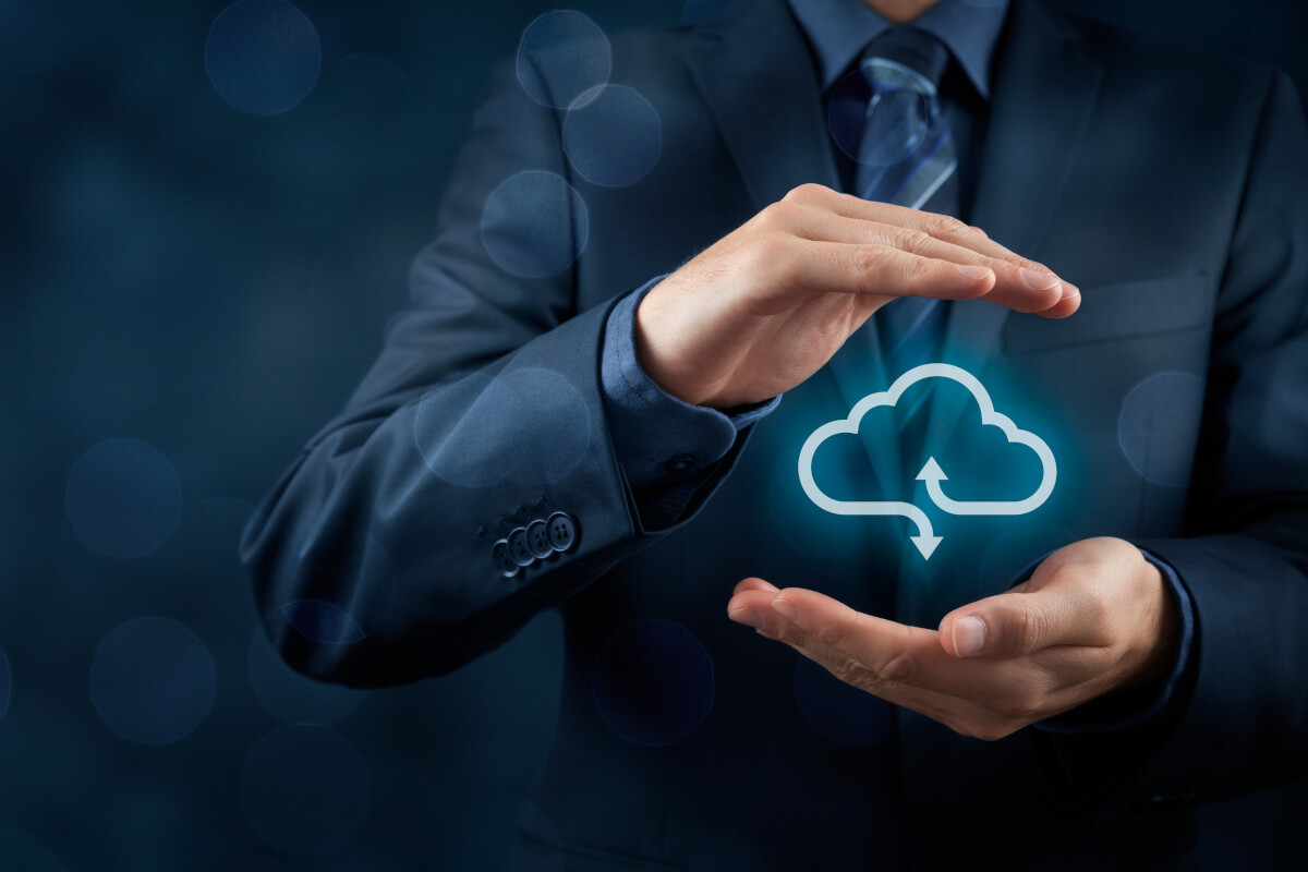 Business professional in dark suit with protective hand gesture over glowing cloud computing icon with upload and download arrows, representing cloud data security and protection services