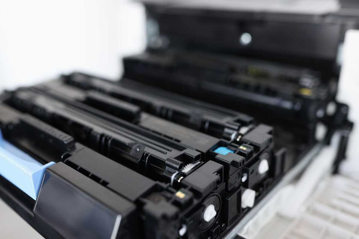 Close-up of black toner cartridges inside an open laser printer, showing intricate details and glossy surfaces.